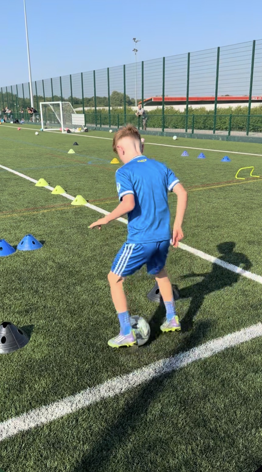 A young footballer practising close control around training cones